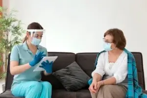 Two masked women in gloves discuss home care and long-term care options in Toronto.